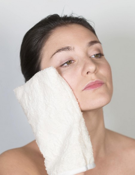 Donna che passa il guanto struccante sulla guancia