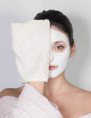 Ragazza che appoggia il guanto struccante sul viso coperto da una maschera di bellezza