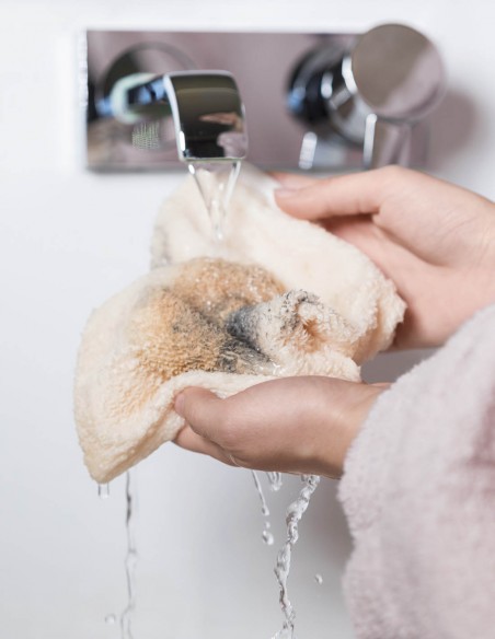 Ragazza che sciacqua il guanto struccante sporco di make-up