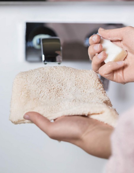 Donna che ha terminato di lavare il guanto struccante con acqua e sapone