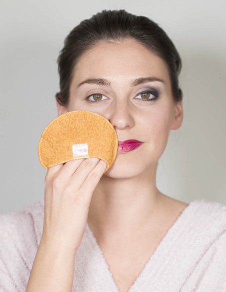 Donna con metà volto struccato con il dischetto struccante, e metà ancora truccato