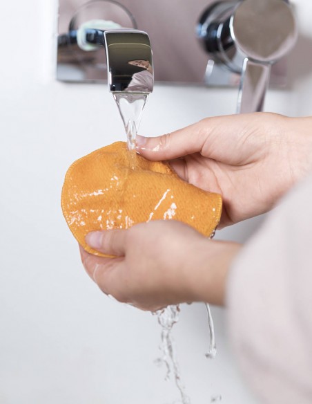 Donna che sciacqua il dischetto struccante sotto il rubinetto