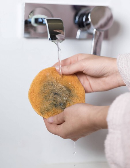 Donna che sciacqua il dischetto struccante sotto acqua corrente