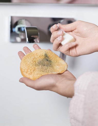 Donna che lava il dischetto struccante con una saponetta delicata