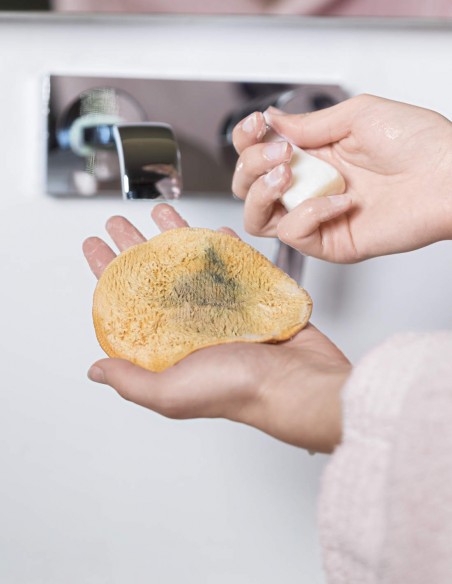 Donna che lava il dischetto struccante con una saponetta delicata