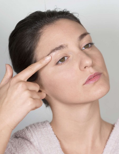 Donna che applica una crema emolliente sotto al sopracciglio Donna che applica una crema emolliente sotto al sopracciglio