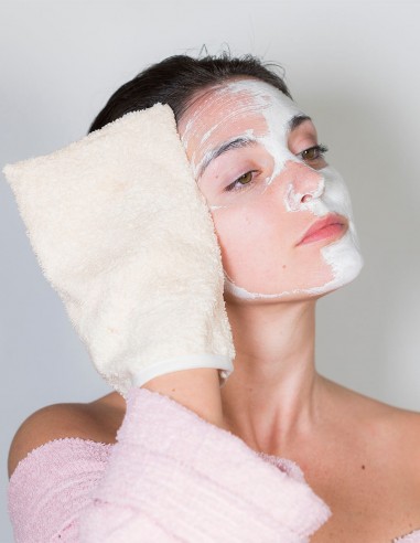 Donna che usa il guanto struccante per rimuovere una maschera di bellezza